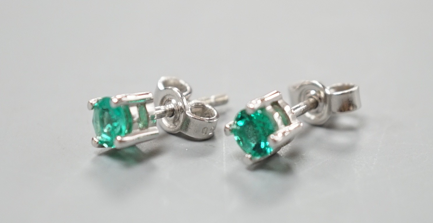 A pair of 750 white metal and solitaire emerald set ear studs, gross weight 1.5 grams, stone diameter approx. 4.2mm.